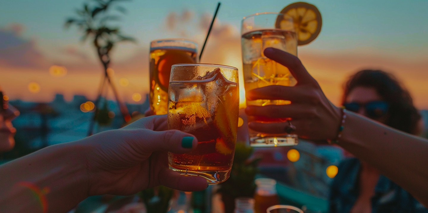 Friends cheering with cocktails at sunset